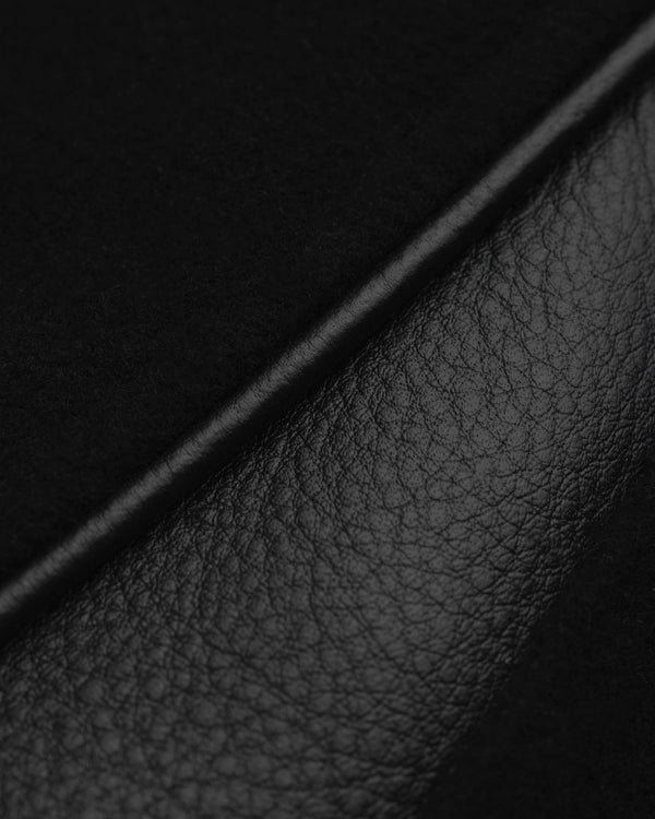 Close-up of textured black leather paneling on the ALD / Olympiacos F.C. Team Leather Jacket, separated by a leather seam.