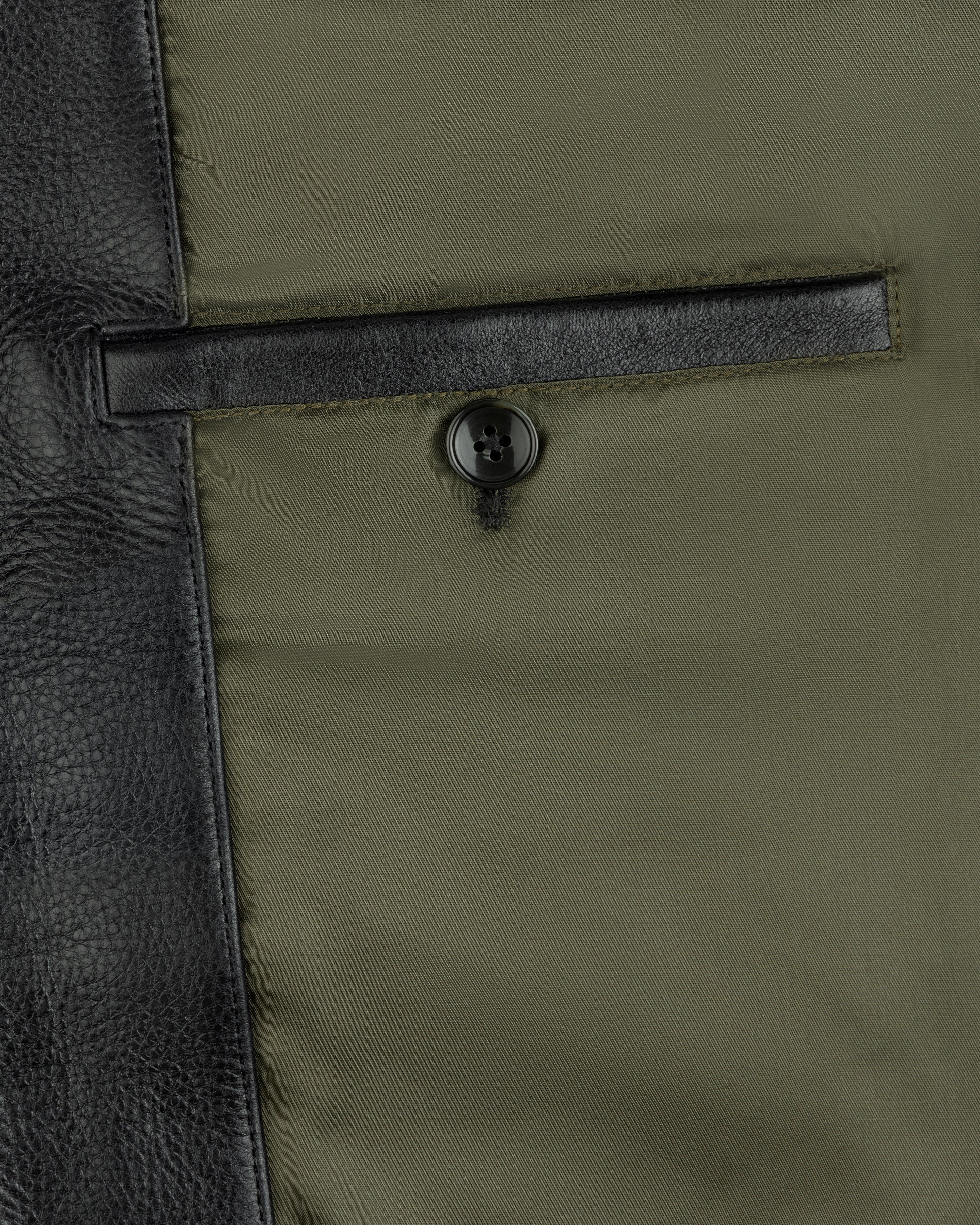 Interior pocket of a Napa Leather Bomber Jacket with a button closure against an olive lining.