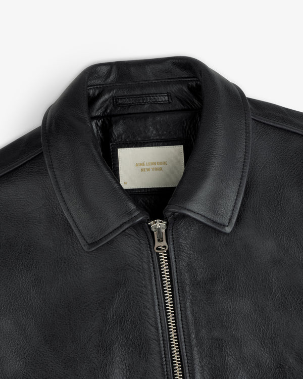 Close-up of a black Napa Leather Bomber Jacket featuring a metal front zipper and a white interior collar tag.