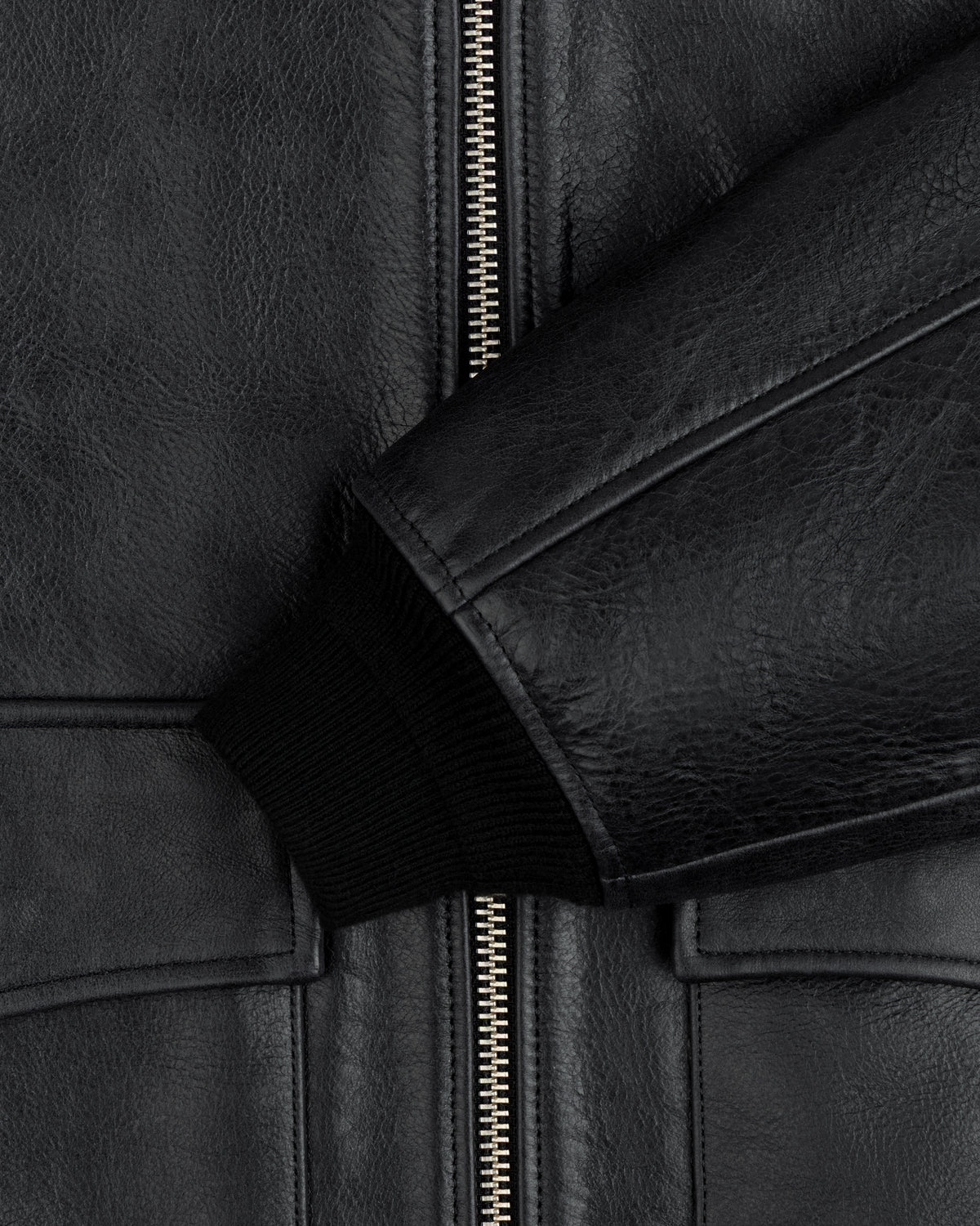 Close-up of a black Napa Leather Bomber Jacket with a central silver zipper and a ribbed knit cuff.