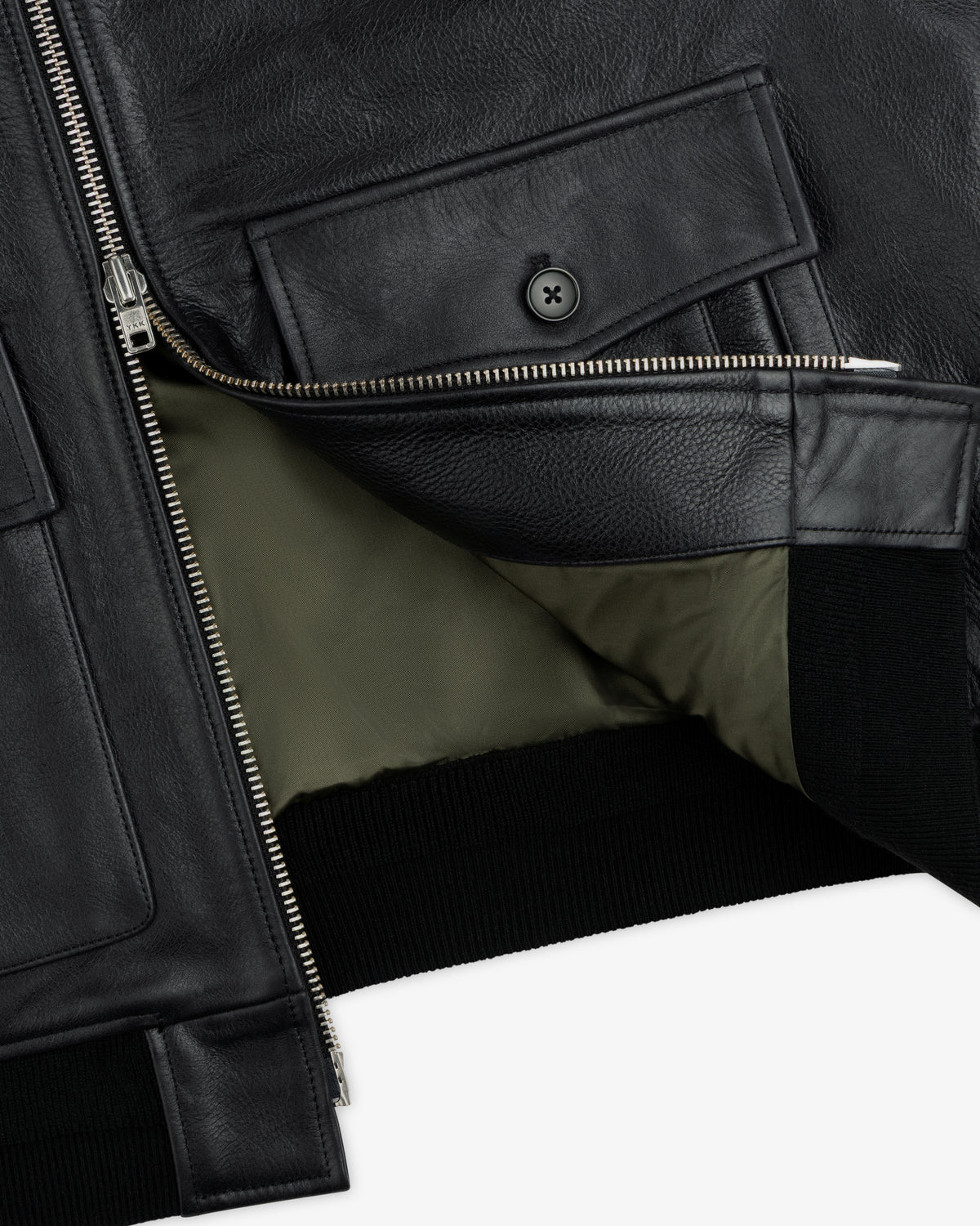 Close-up of a Napa Leather Bomber Jacket showing the black leather, silver zipper, front flap pocket, and olive lining.