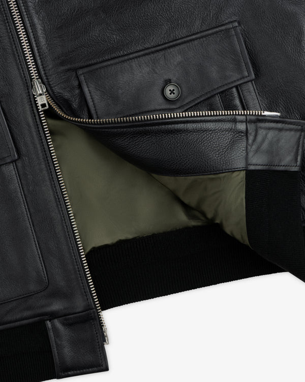 Close-up of a Napa Leather Bomber Jacket showing the black leather, silver zipper, front flap pocket, and olive lining.