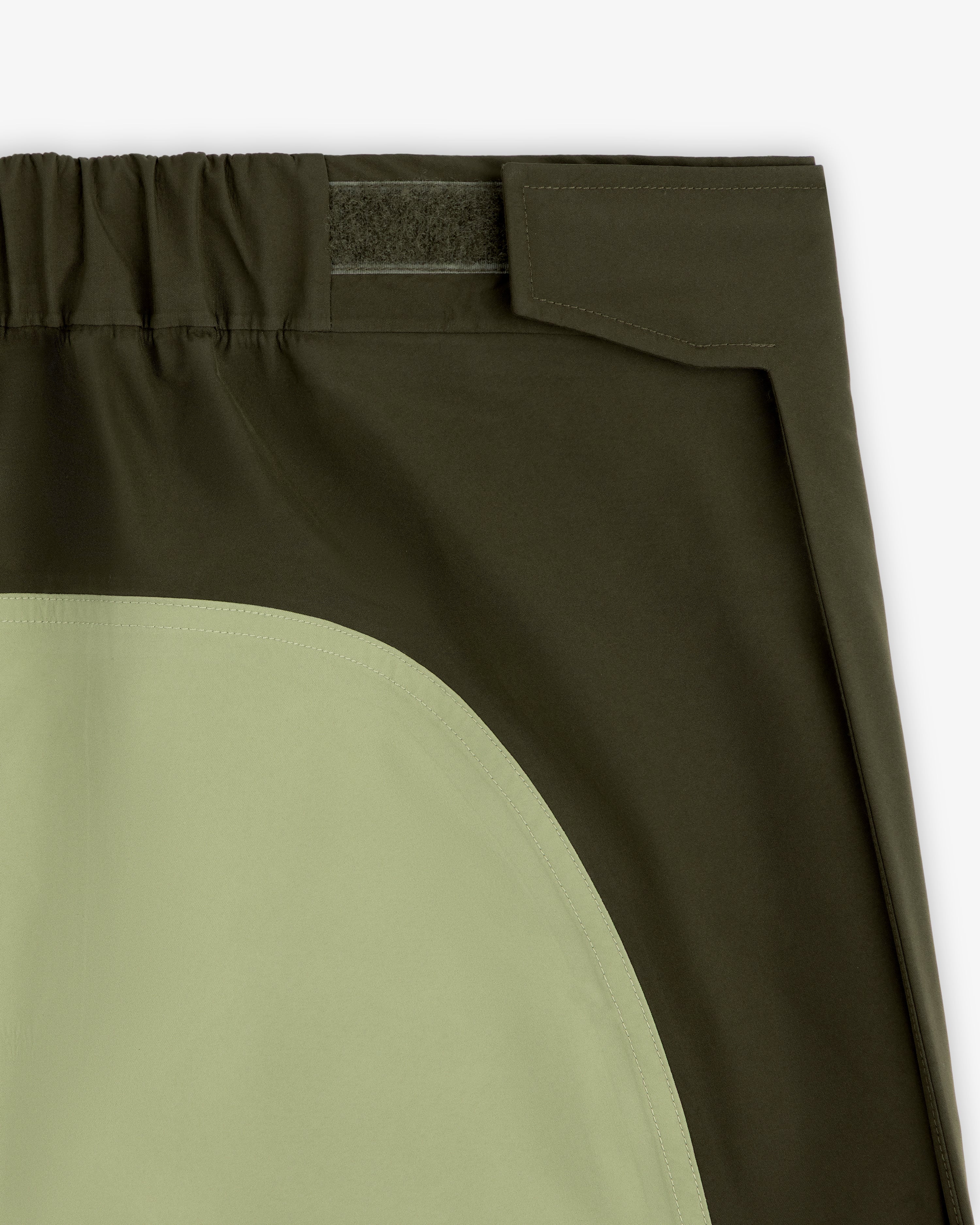 Close-up of ALD/The North Face GORE-TEX Pant featuring olive patch, elastic waist, and hook-and-loop fastener.