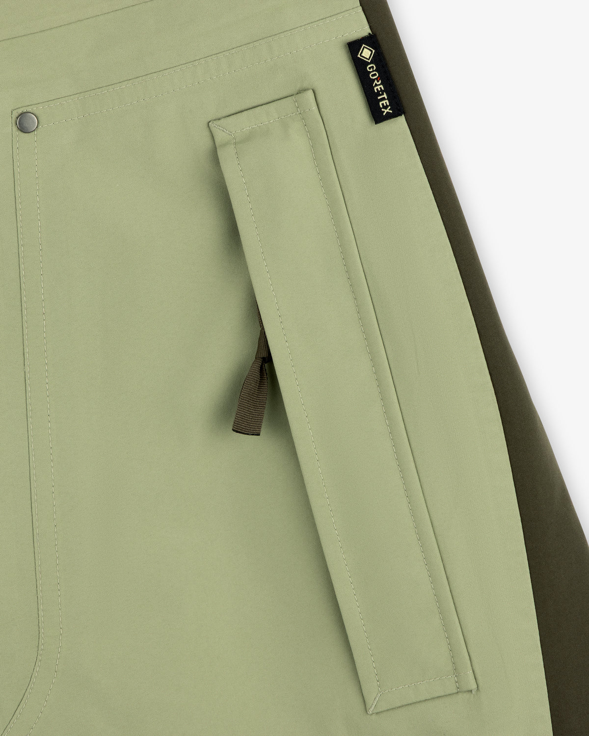 Close-up of ALD / The North Face GORE-TEX Pant pocket in light green with black zipper pull and olive side panel.