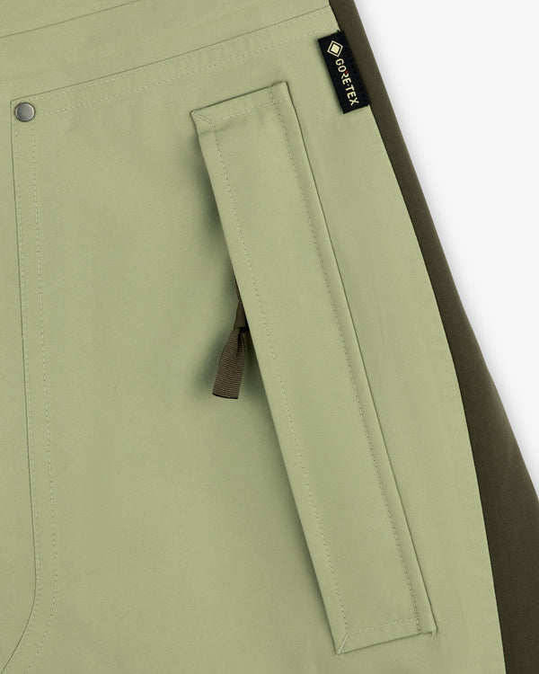 Close-up of ALD / The North Face GORE-TEX Pant pocket in light green with black zipper pull and olive side panel.