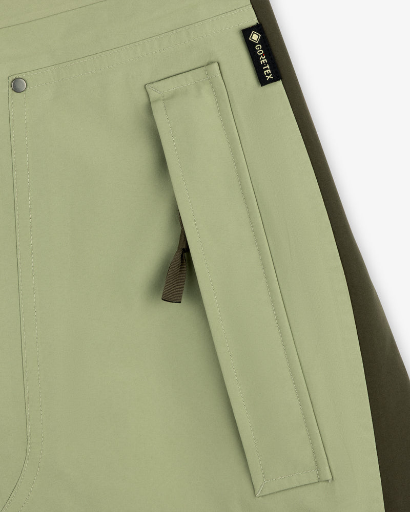 Close-up of ALD / The North Face GORE-TEX Pant pocket in light green with black zipper pull and olive side panel.