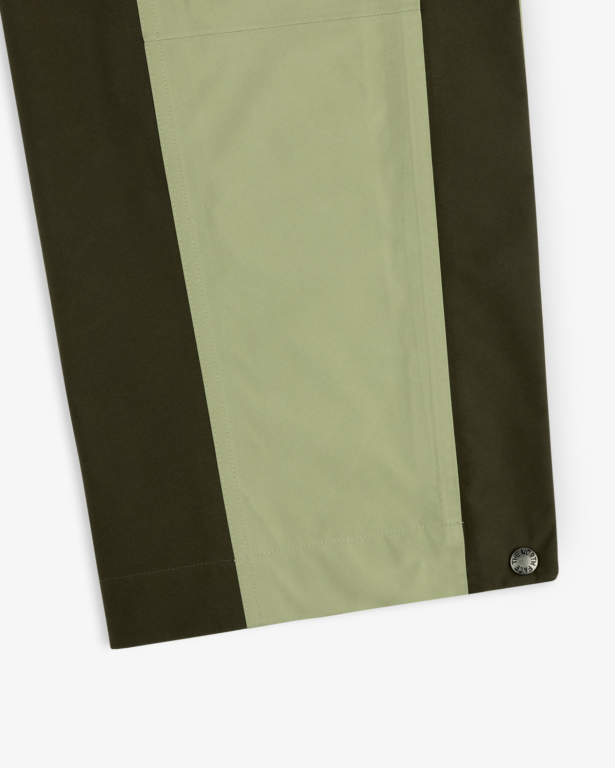 Close-up of ALD / The North Face GORE-TEX Pant with olive and light green panels, metallic button at lower right.