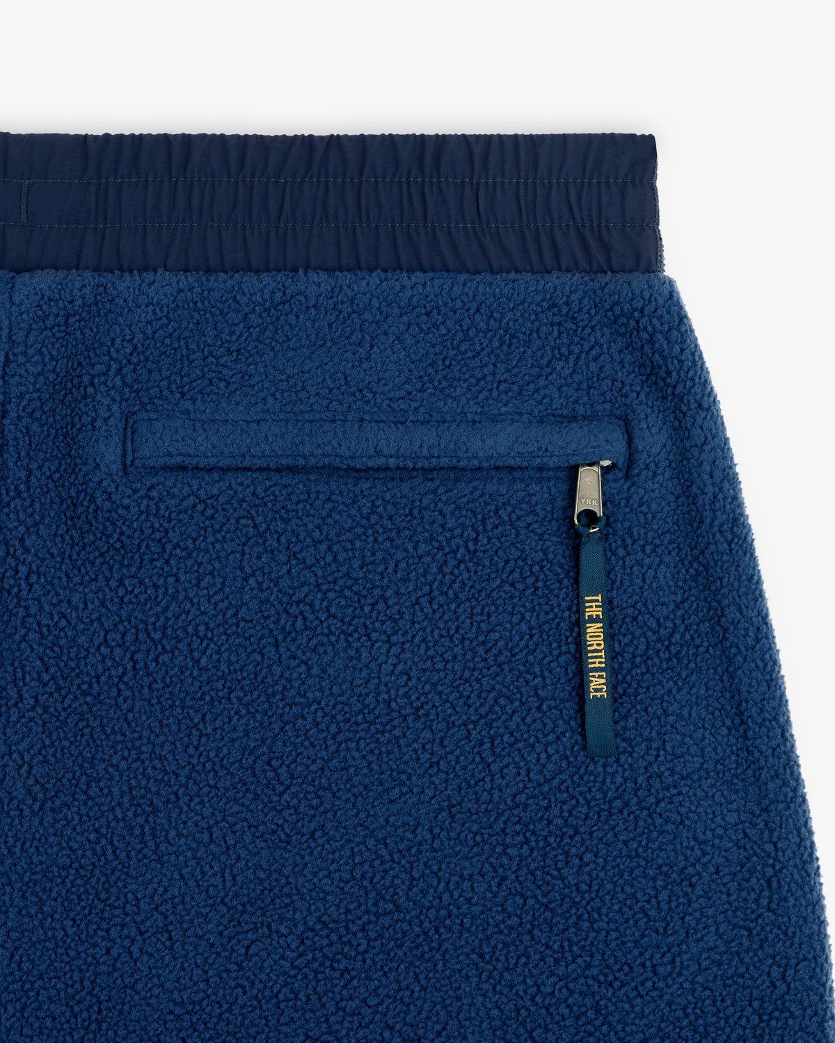 Close-up of ALD / The North Face Denali Fleece Pant with navy waistband and zippered pocket with yellow pull.