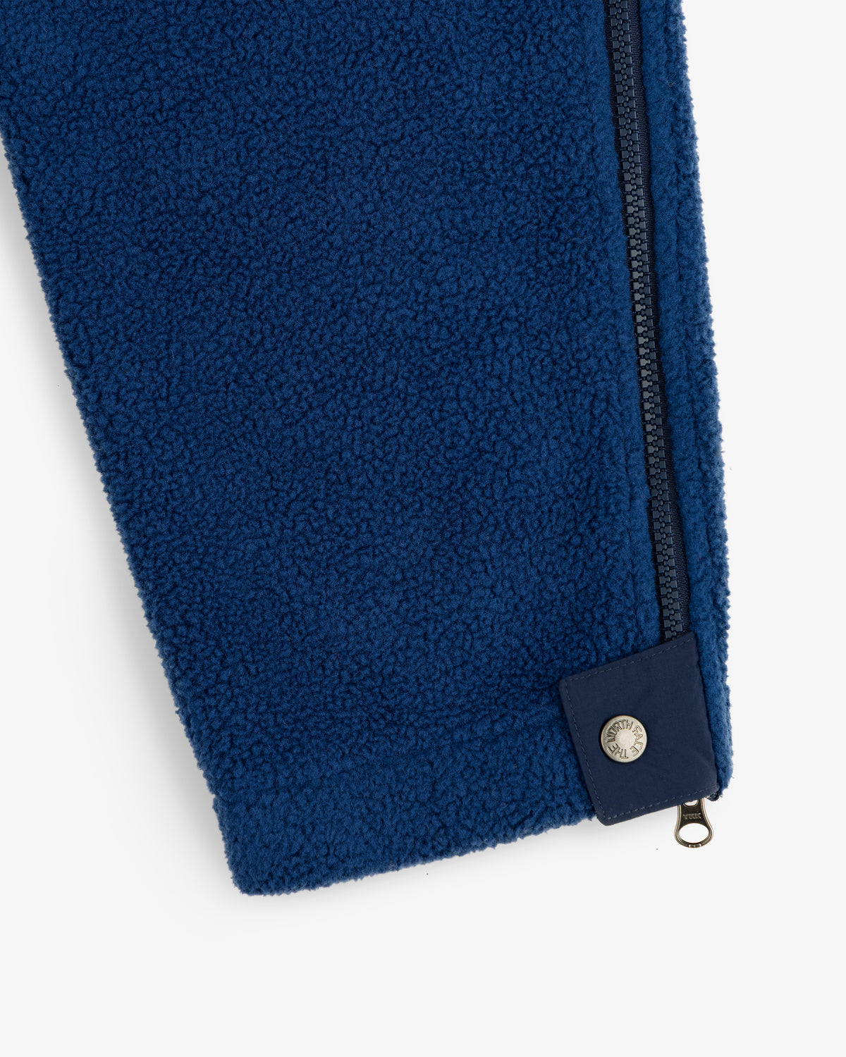 Close-up of ALD / The North Face Denali Fleece Pant in blue, featuring a navy zipper and snap button at the cuff.