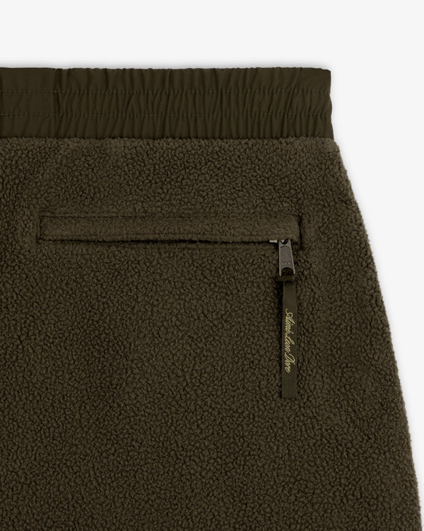 Close-up of ALD / The North Face Denali Fleece Pant in olive green with zippered pocket and elastic waistband.