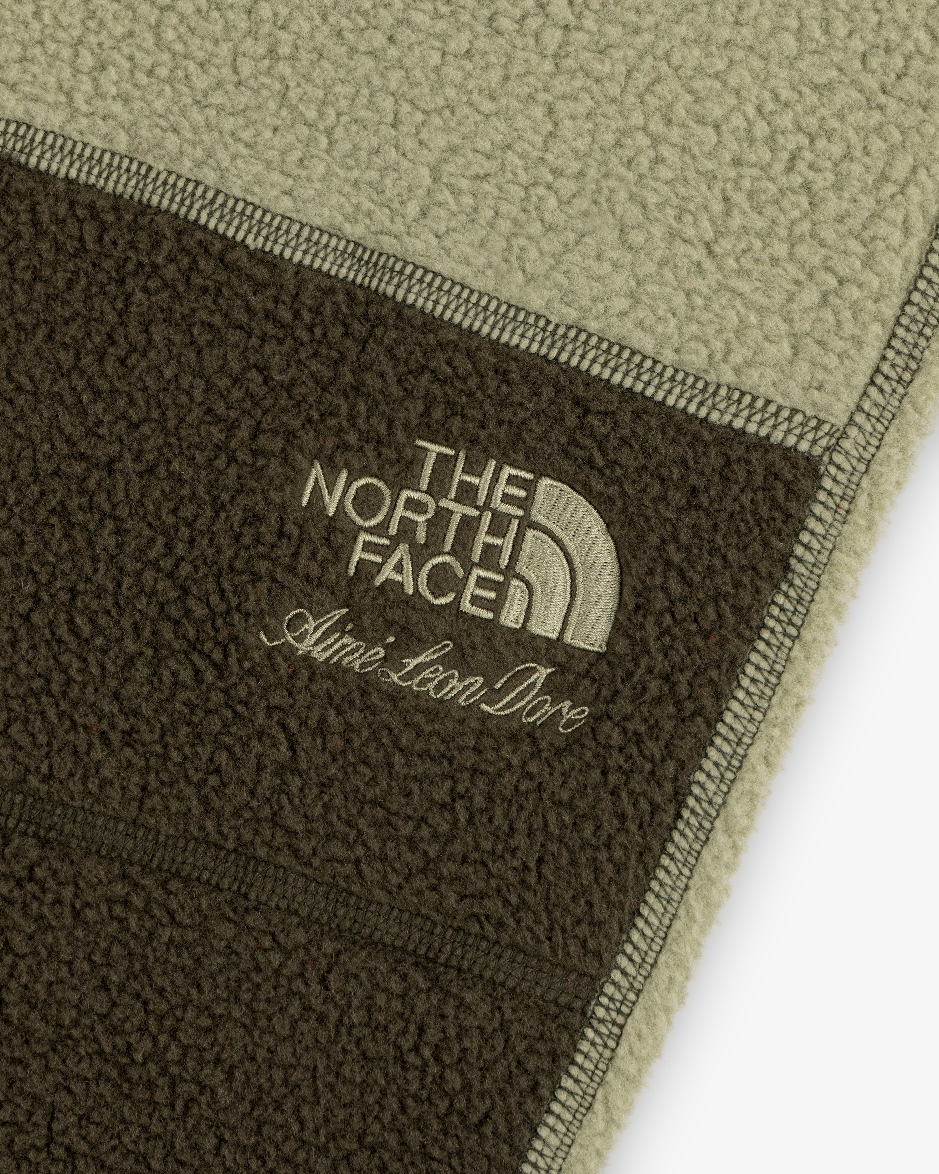 Close-up of green and brown ALD / The North Face Denali Fleece Pant with embroidered logos.