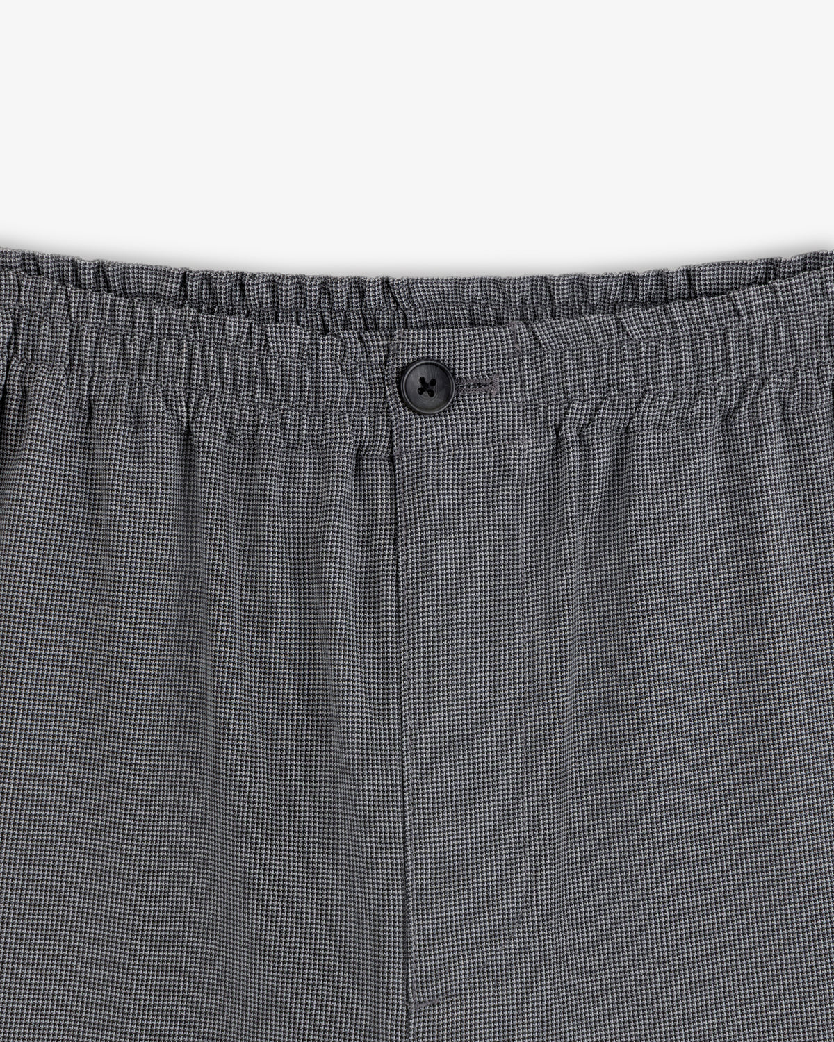 Close-up of Houndstooth Elasticated Waist Trouser with gray checks, stretchy waistband, and a single black button.