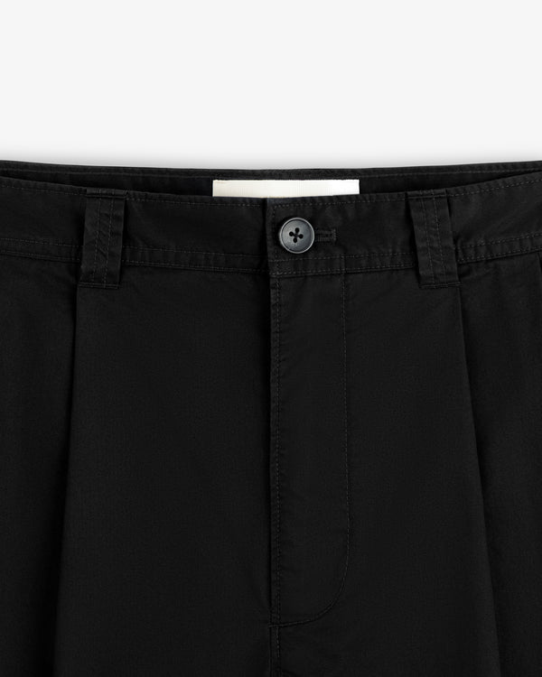 Close-up of the waistband and button of Double Pleated Officer Pant featuring belt loops, pleats, and visible stitching.