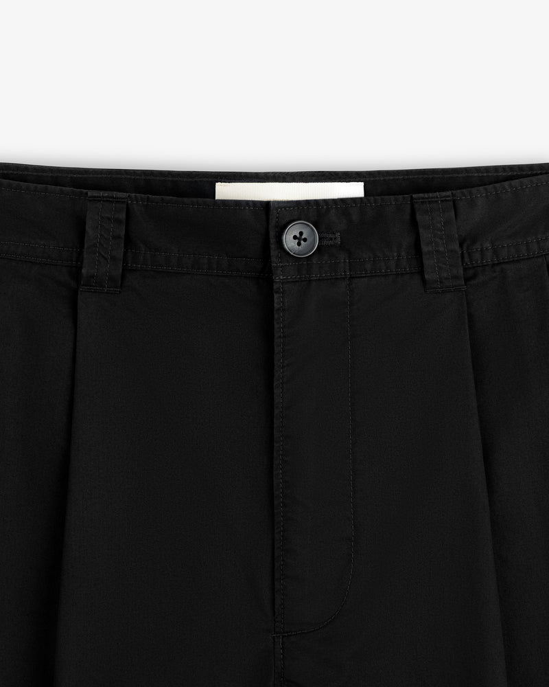 Close-up of the waistband and button of Double Pleated Officer Pant featuring belt loops, pleats, and visible stitching.