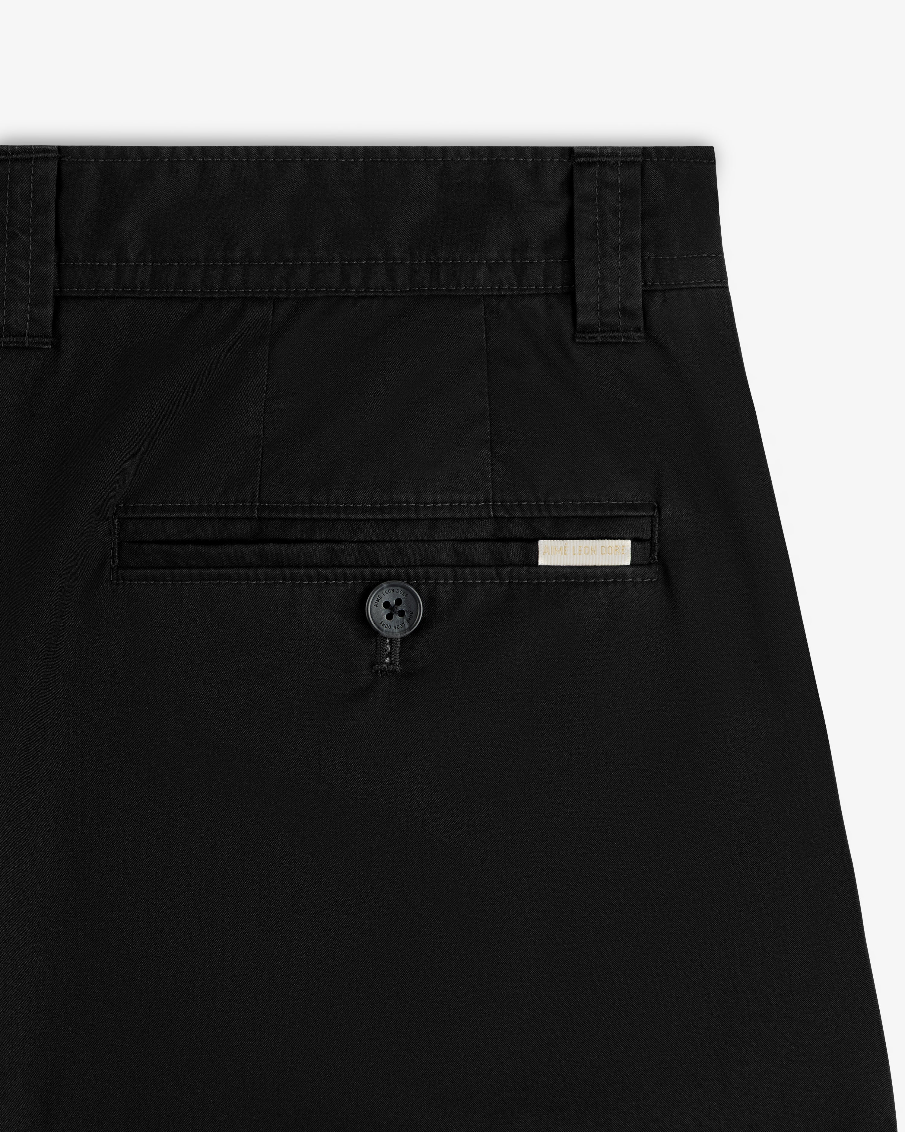 Close-up of Double Pleated Officer Pant’s back pocket with button and small rectangular label above the pocket.