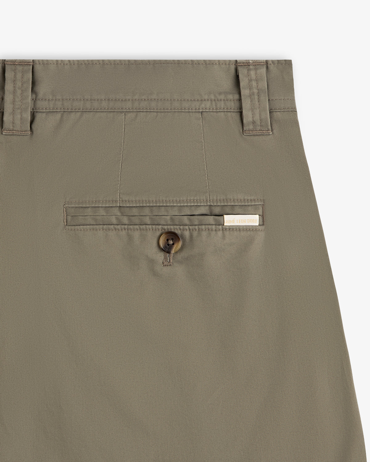Close-up of Double Pleated Officer Pant’s back pocket with button closure and label above the pocket.