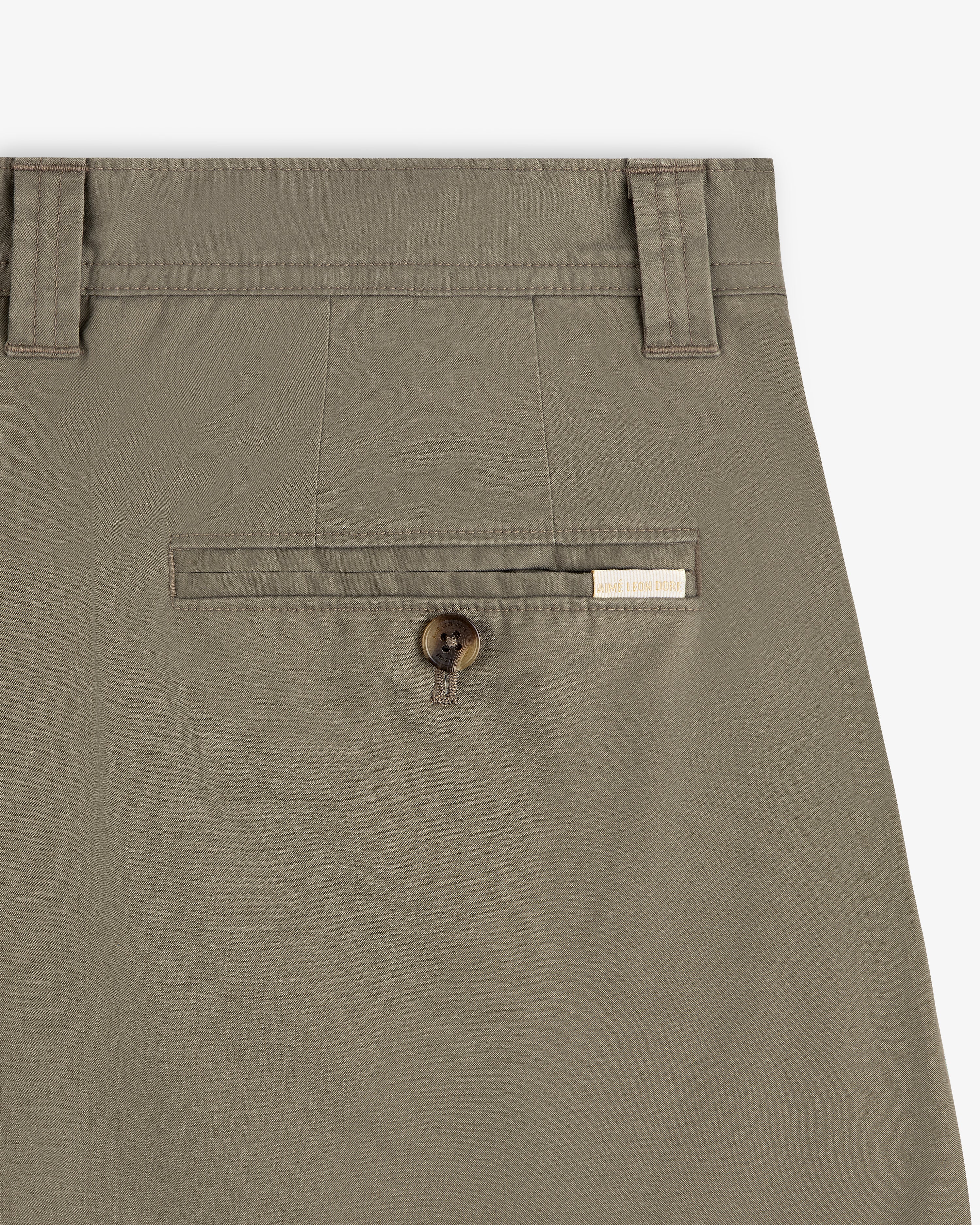 Close-up of Double Pleated Officer Pant’s back pocket with button closure and label above the pocket.