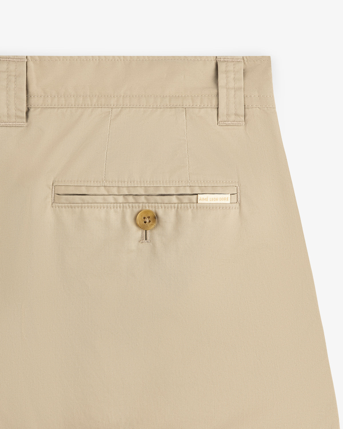 Close-up of Double Pleated Officer Pant’s back pocket with button closure, belt loops, and label above the pocket.