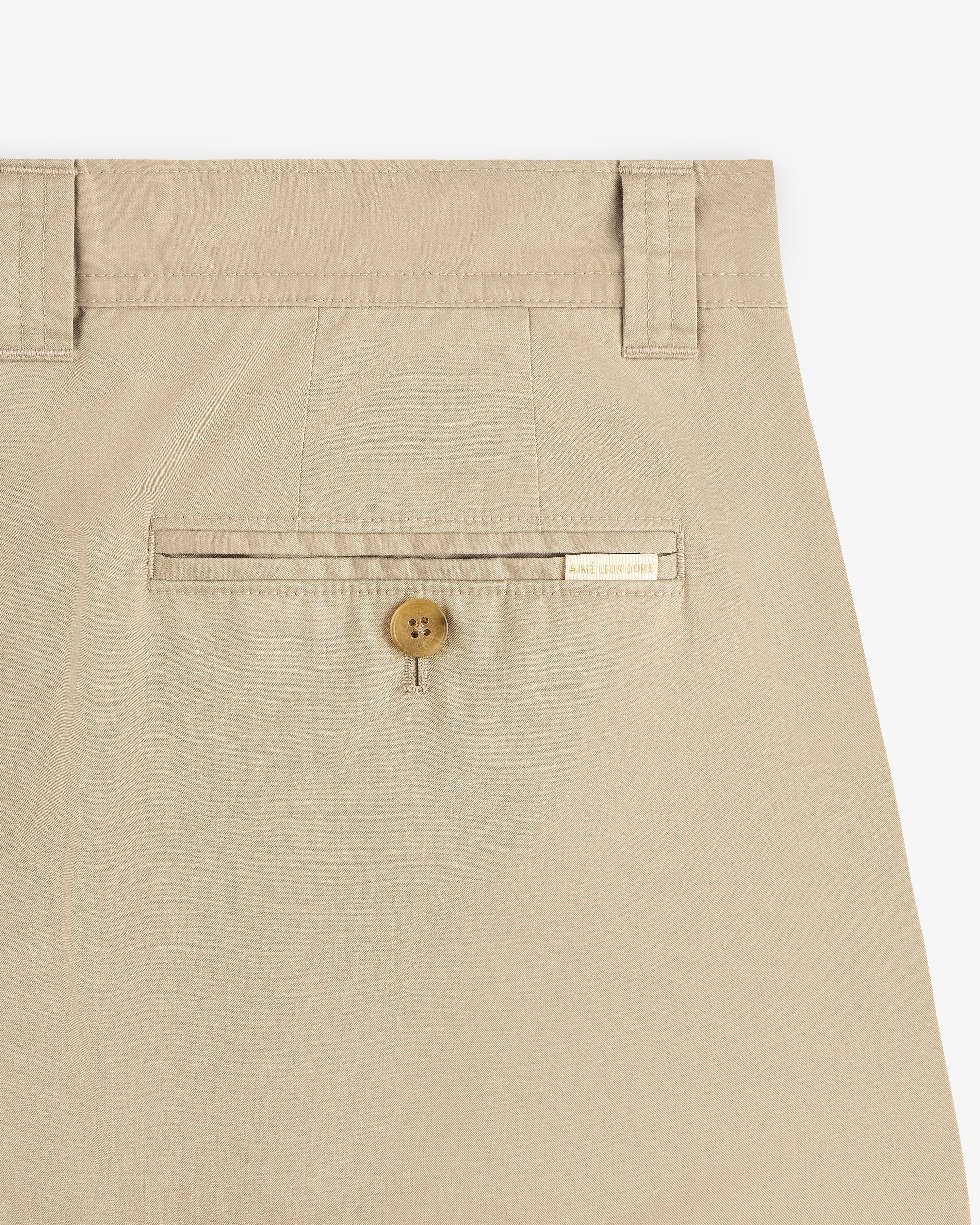 Close-up of Double Pleated Officer Pant’s back pocket with button closure, belt loops, and label above the pocket.