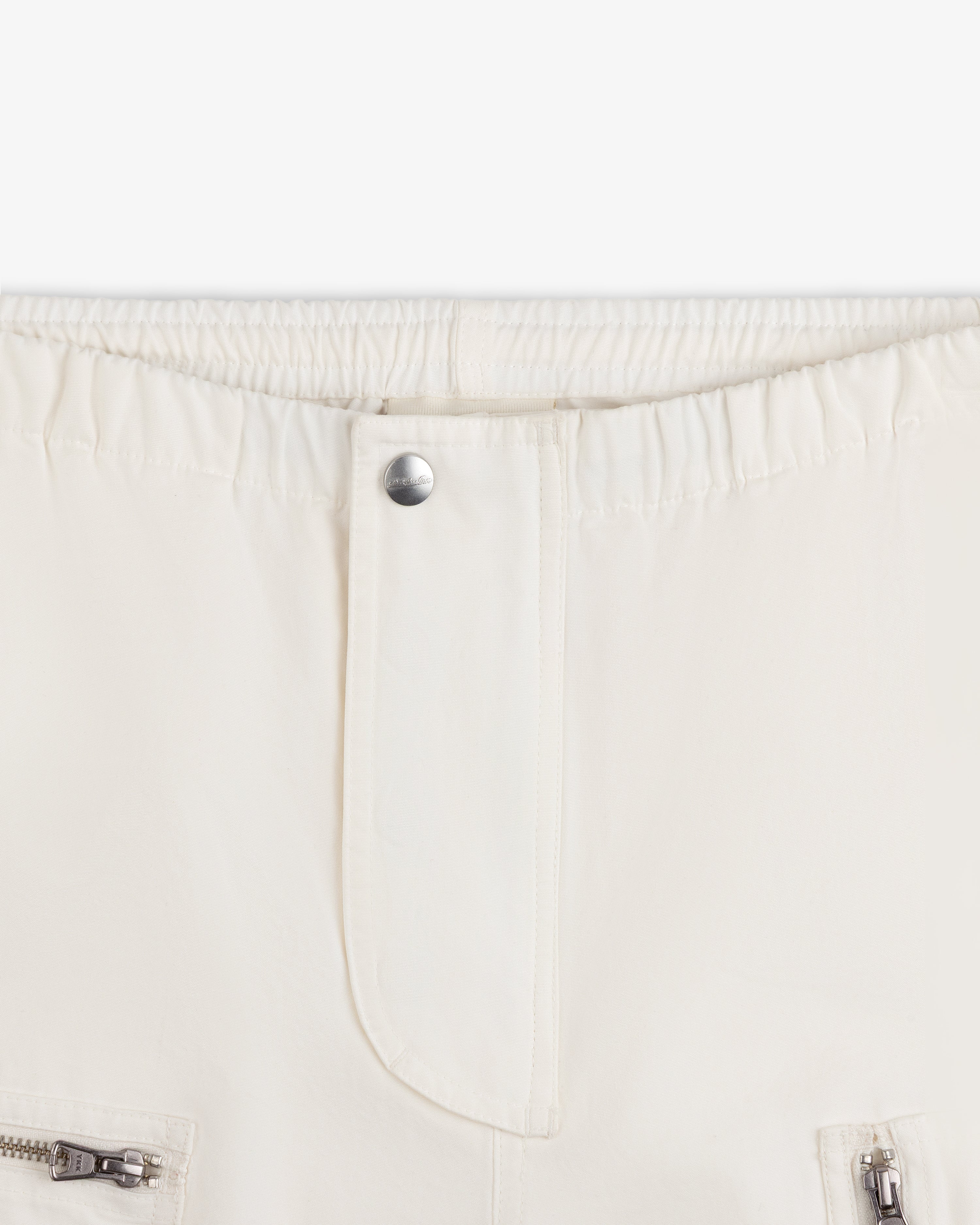 Garment Washed Aviator Pants in off-white with an elasticized waistband, center button closure, and zippered pockets.