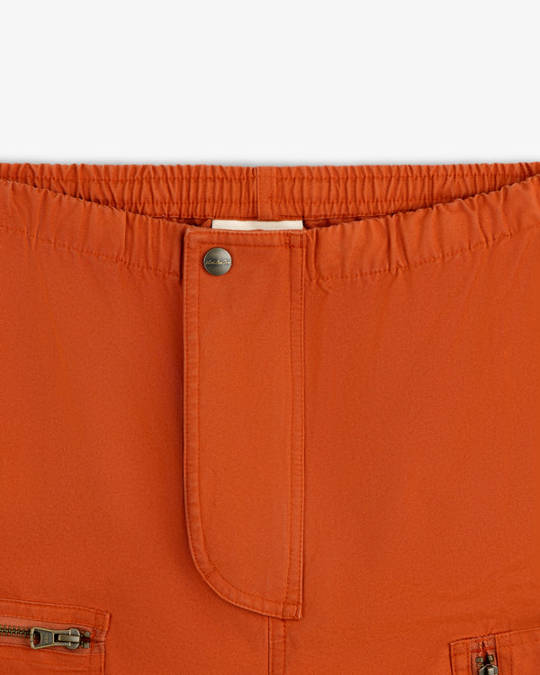 Close-up of rust-colored Garment Washed Aviator Pants with an elastic waist, front button, and zippered pockets.