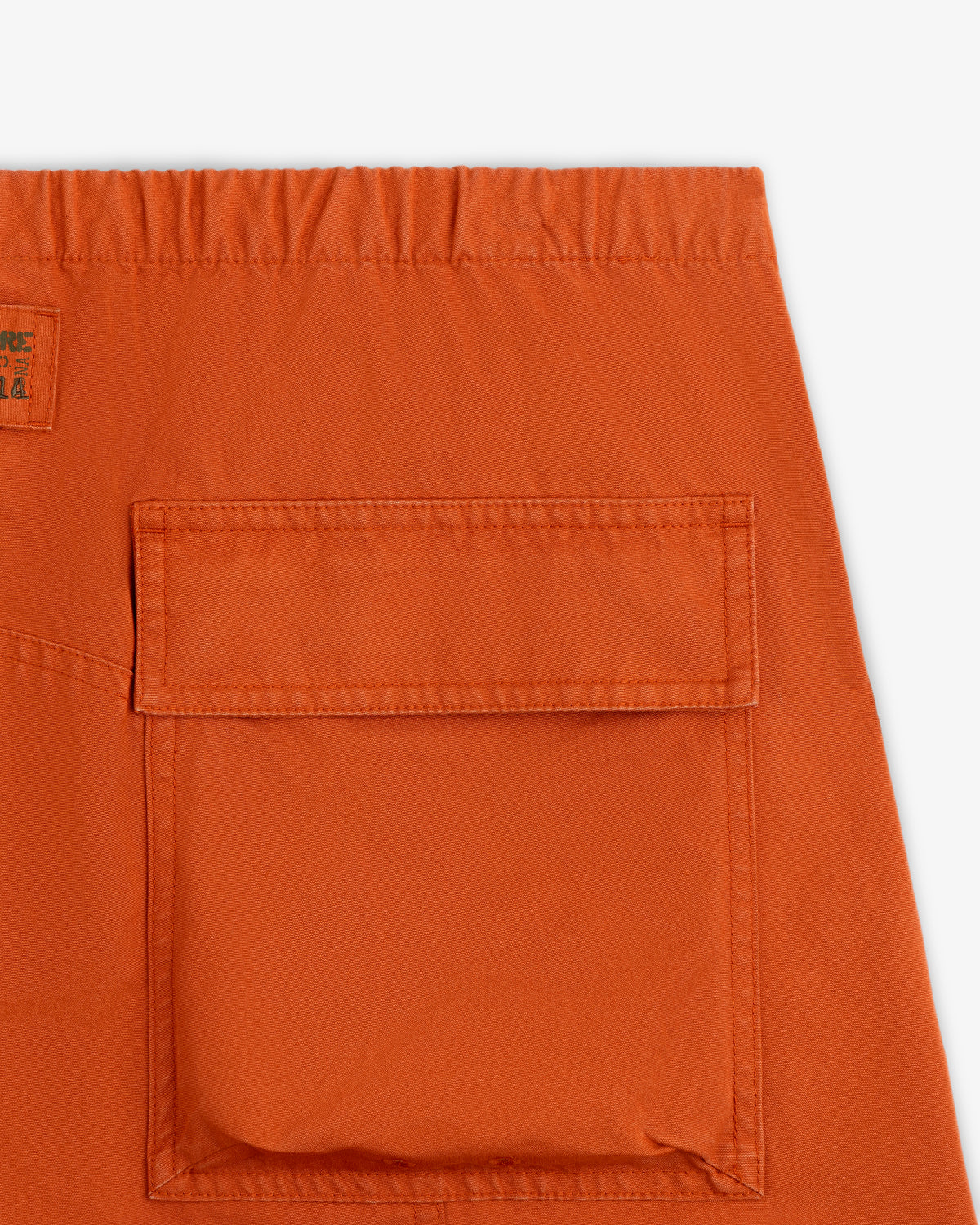 Close-up of the back pocket and elastic waistband of rust-orange Garment Washed Aviator Pant.