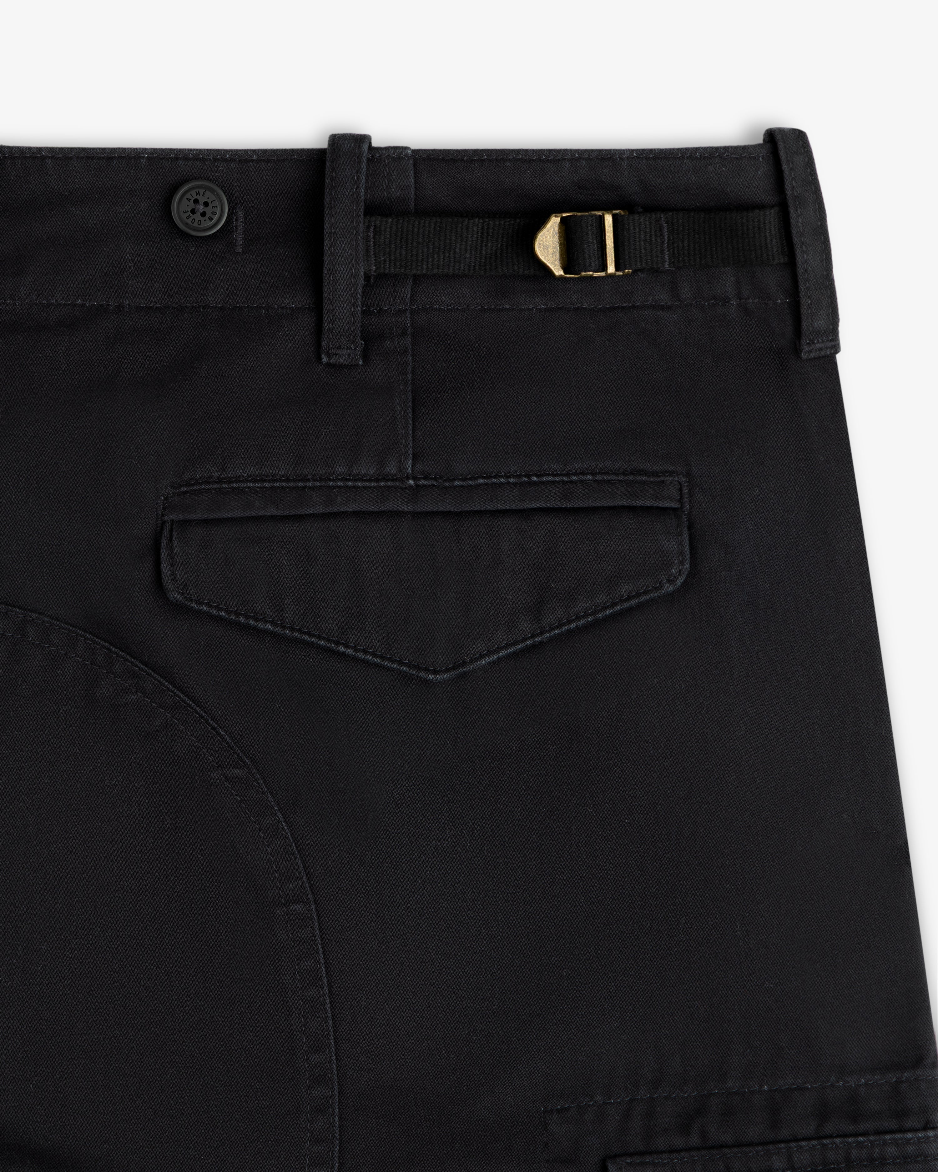 Close-up of Fatigue Pant in black featuring a flap pocket, belt loop, button, and gold buckle at the waistband.