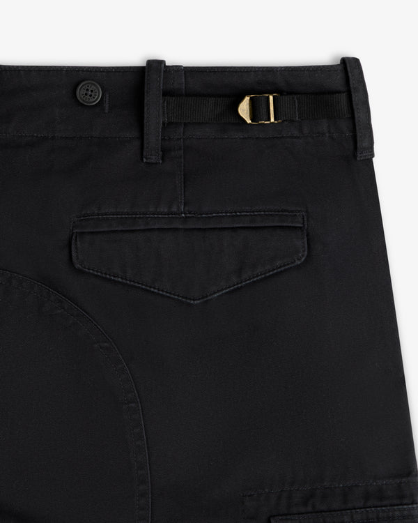 Close-up of Fatigue Pant in black featuring a flap pocket, belt loop, button, and gold buckle at the waistband.