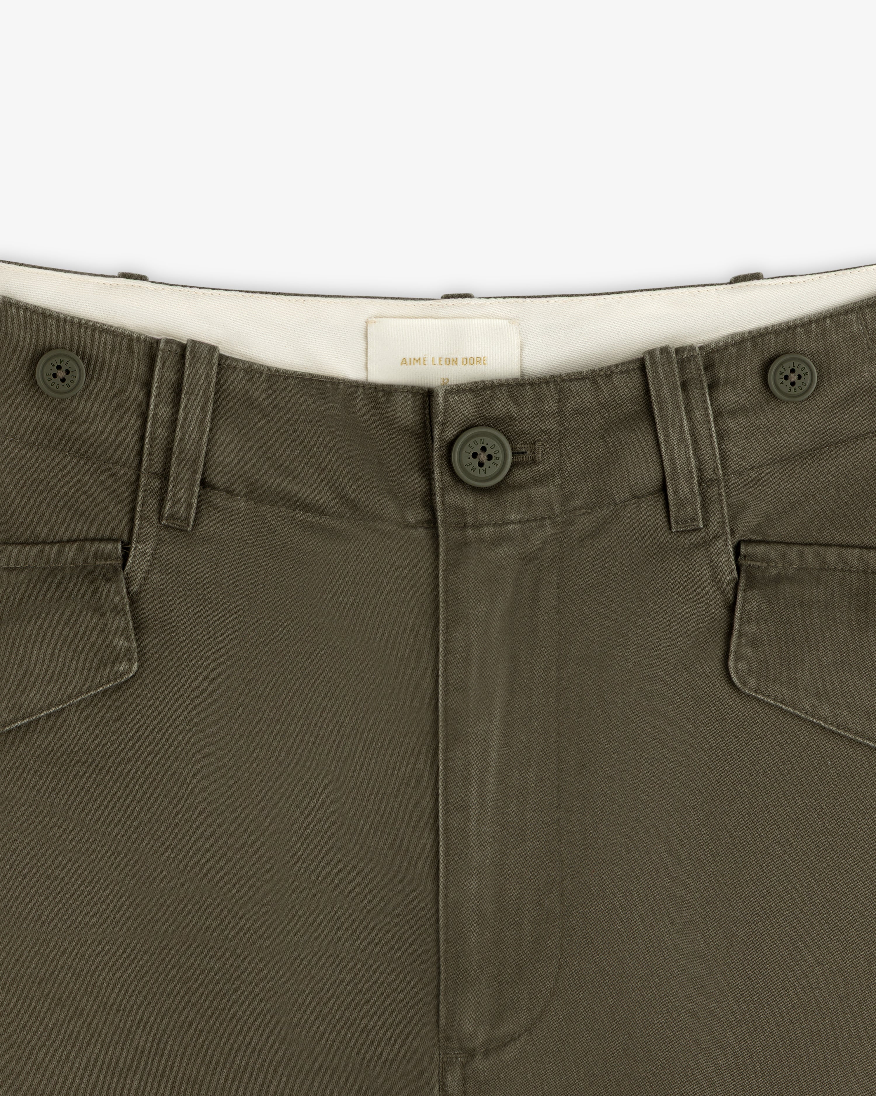 Close-up of Fatigue Pant in olive green with two buttons, belt loops, and white inner waistband.