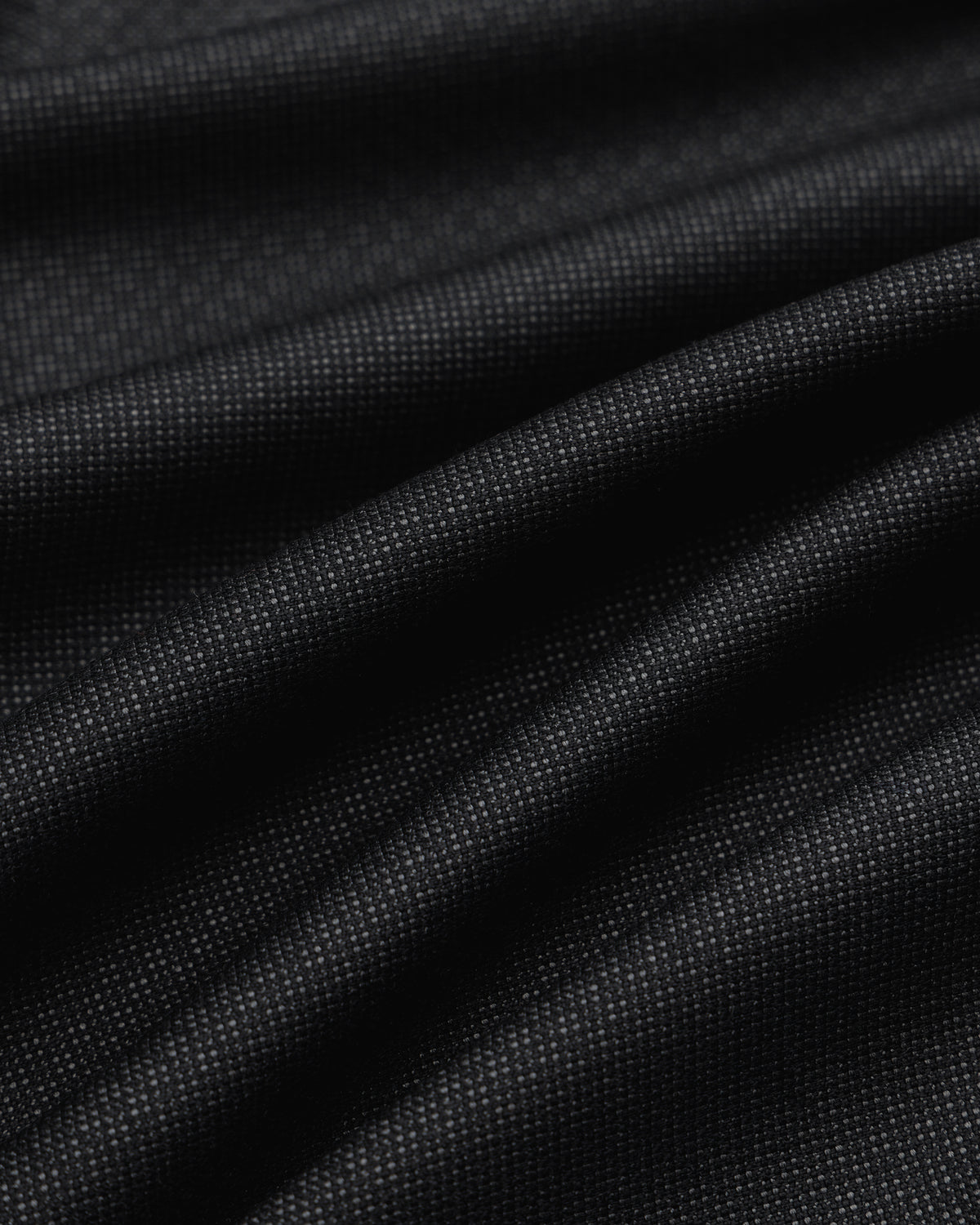 Close-up of black Double Pleated Wool Jacquard Suit Trouser fabric with a fine, textured weave and subtle pleats.