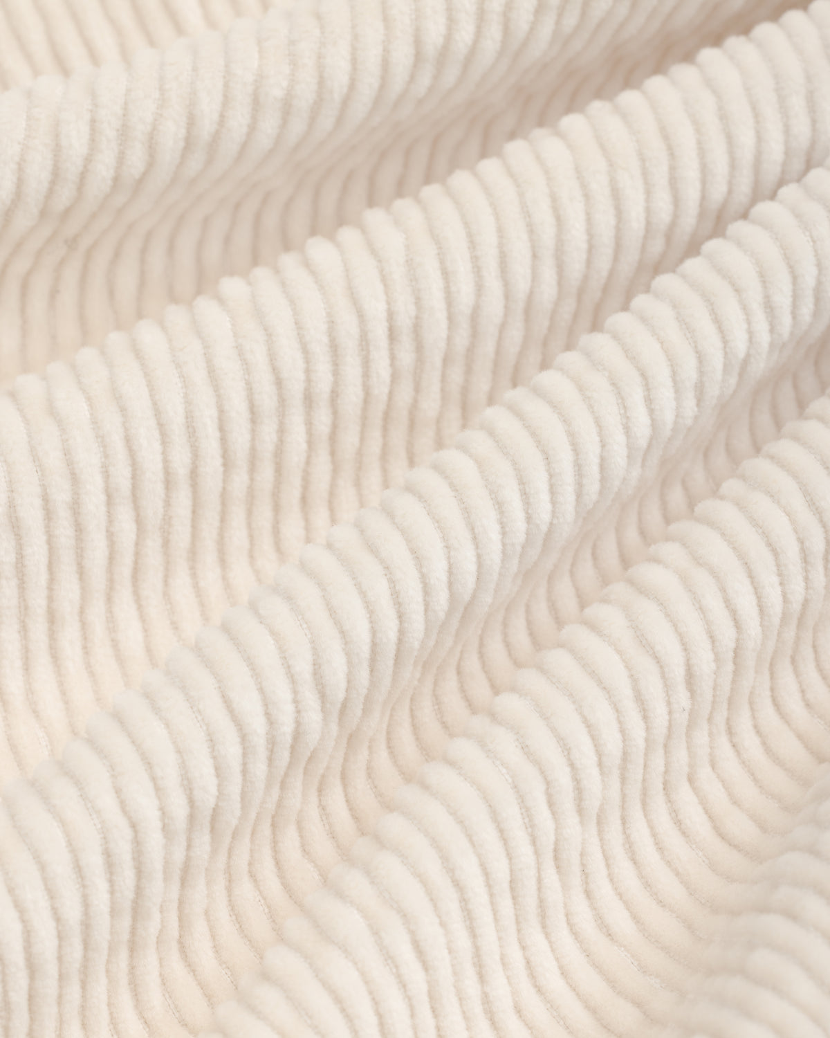 Close-up of off-white Double Pleated Corduroy Trouser fabric with visible vertical ridges and soft folds.
