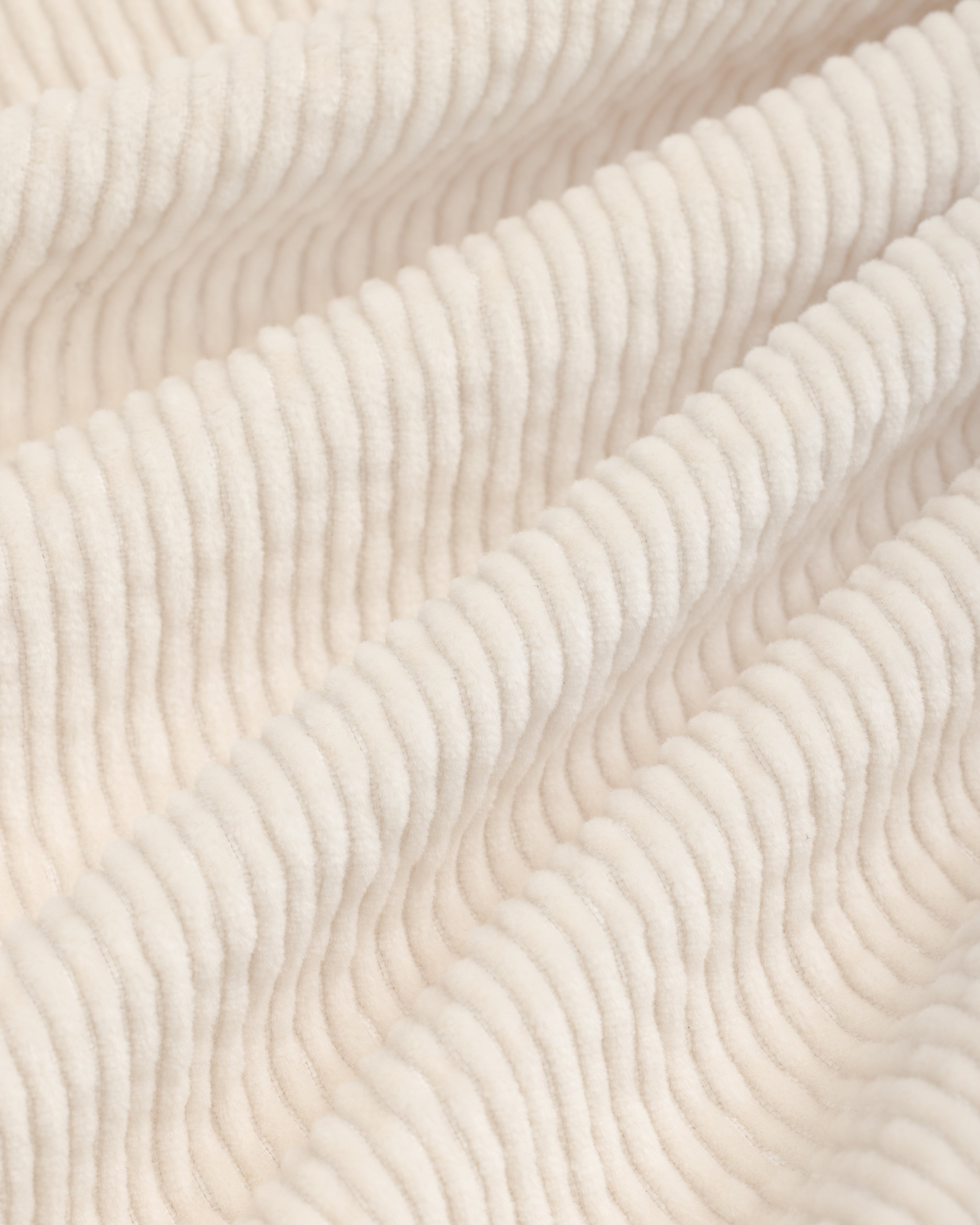 Close-up of off-white Double Pleated Corduroy Trouser fabric with visible vertical ridges and soft folds.