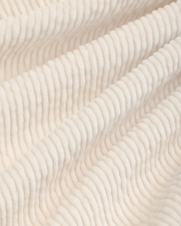 Close-up of off-white Double Pleated Corduroy Trouser fabric with visible vertical ridges and soft folds.