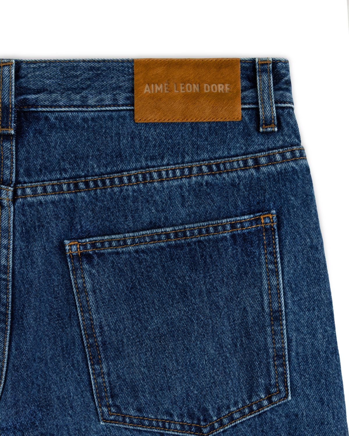 Back pocket of dark wash ALD Relaxed Fit Denim jeans with a tan leather brand patch on the waistband.