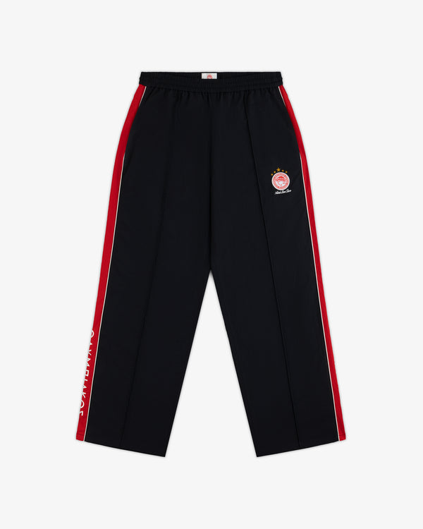 ALD / Olympiacos F.C. Nylon Track Pant in black with red and white side stripes, a circular sports emblem, and leg text.