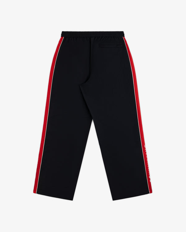 Back view of black ALD / Olympiacos F.C. Nylon Track Pant with red and white stripes down the sides.
