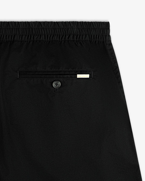 Close-up of Cotton Casual Short in black with an elastic waistband, back button pocket, and metal tag.