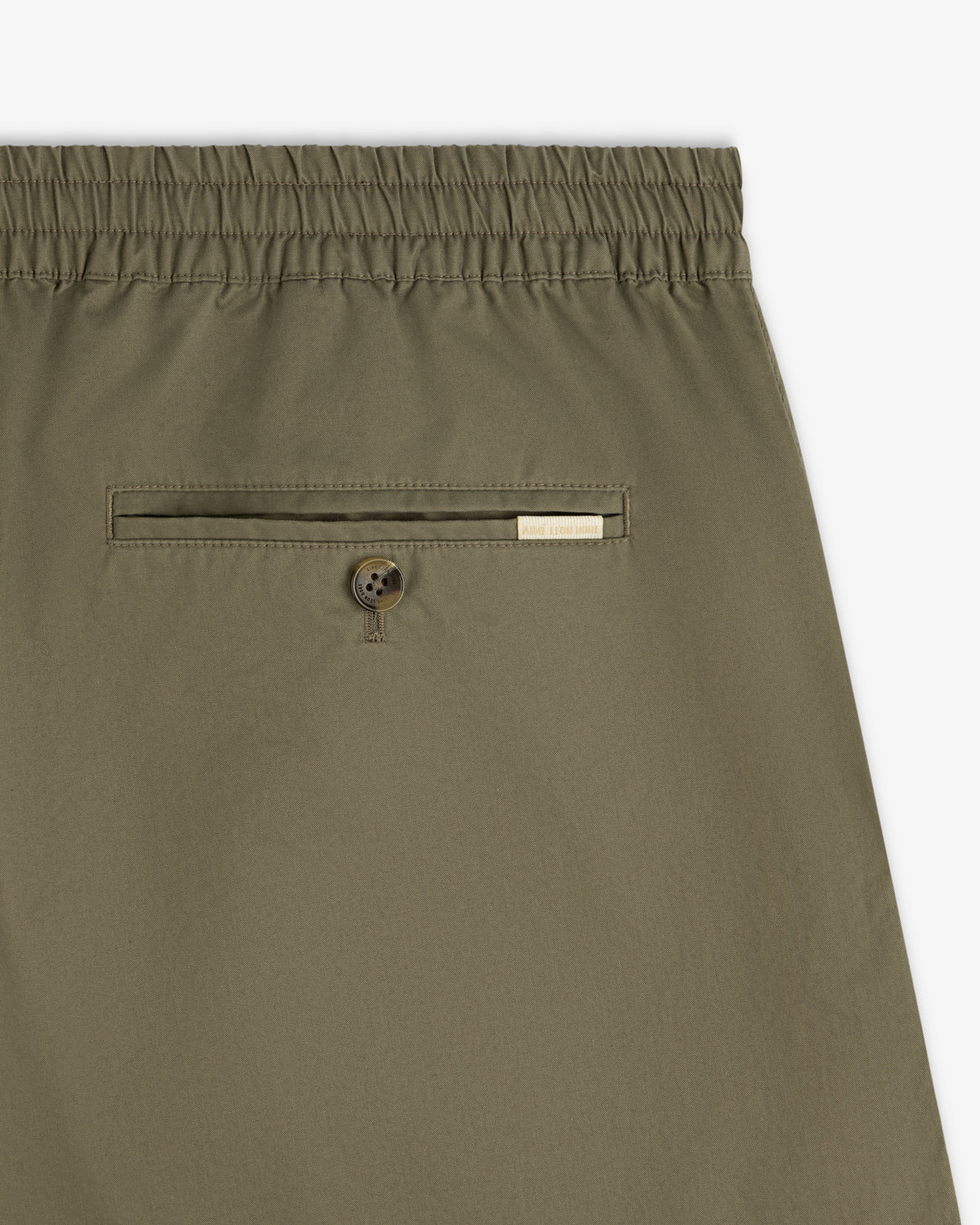 Close-up of Cotton Casual Short in olive green with elastic waist, back button pocket, and a small label.