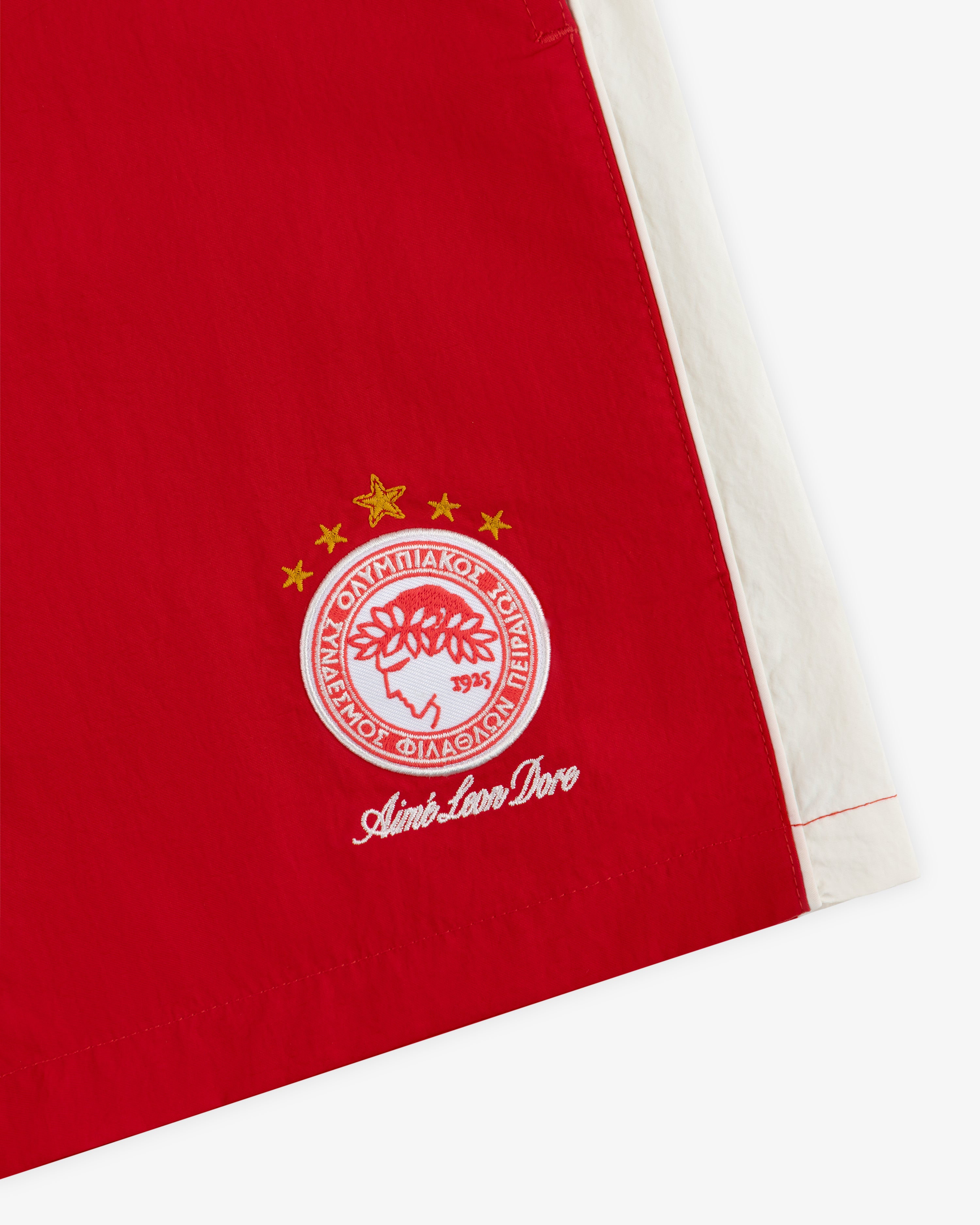 ALD / Olympiacos F.C. Nylon Training Short in red nylon with a white side stripe and embroidered circular emblem.