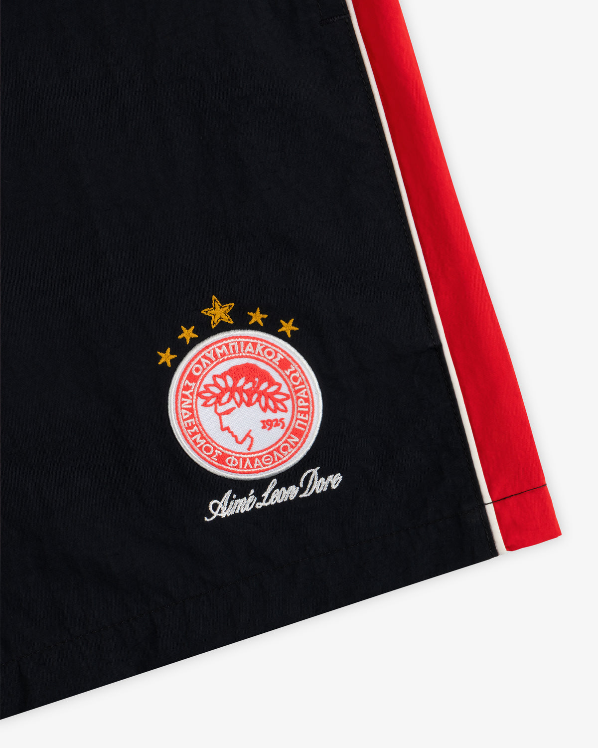 ALD / Olympiacos F.C. Nylon Training Short: black shorts with a red side stripe and a red/white crest with four stars.