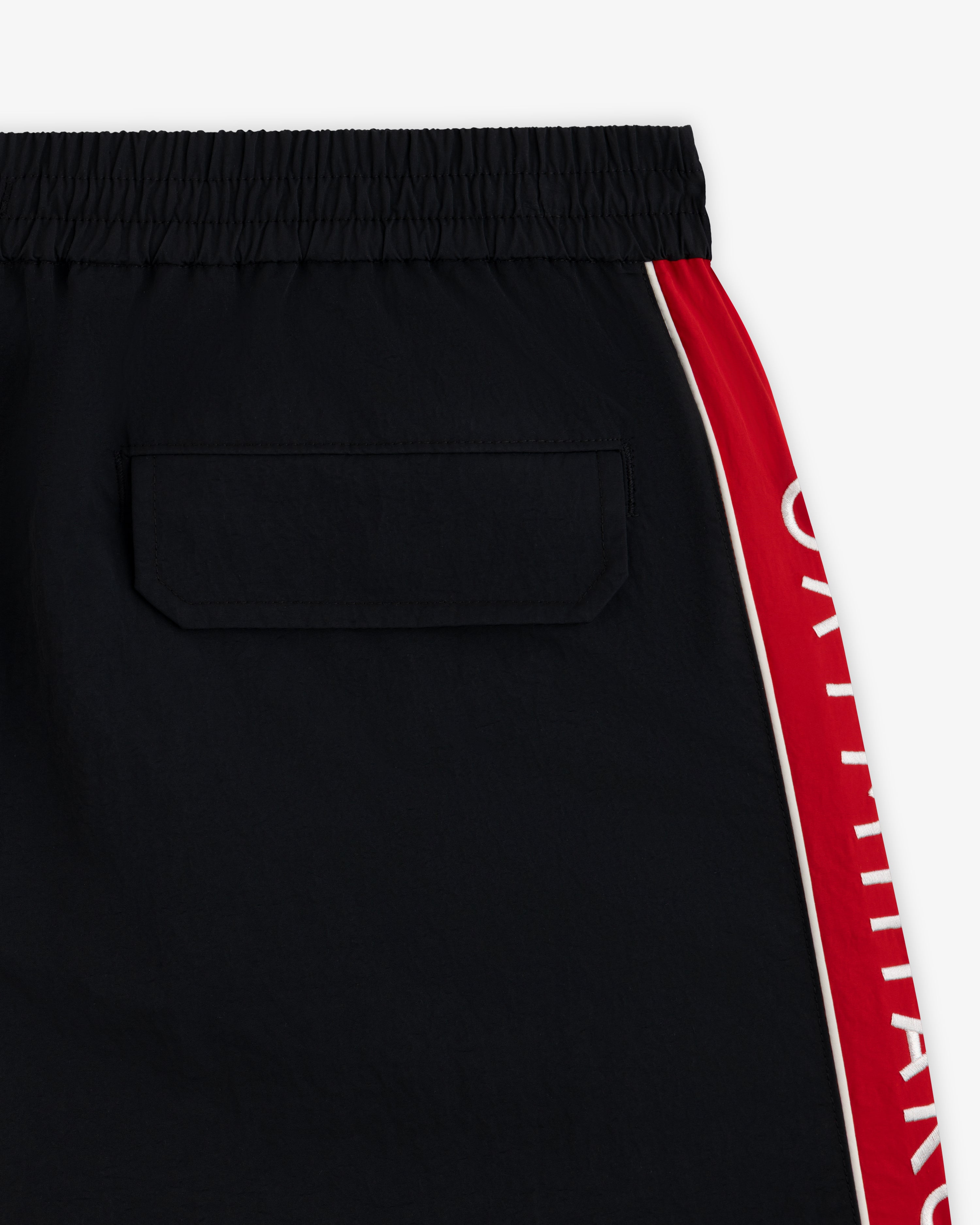 ALD / Olympiacos F.C. Nylon Training Short: black athletic shorts with a back pocket and a red side stripe with white text.