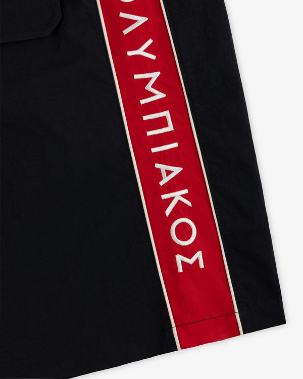 ALD / Olympiacos F.C. Nylon Training Short: black nylon shorts with a vertical red side stripe and white Greek lettering.