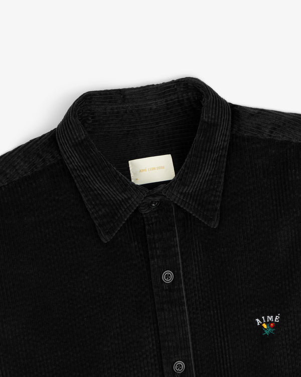 Black Corduroy Leon Overshirt with a small floral embroidered logo on the chest.