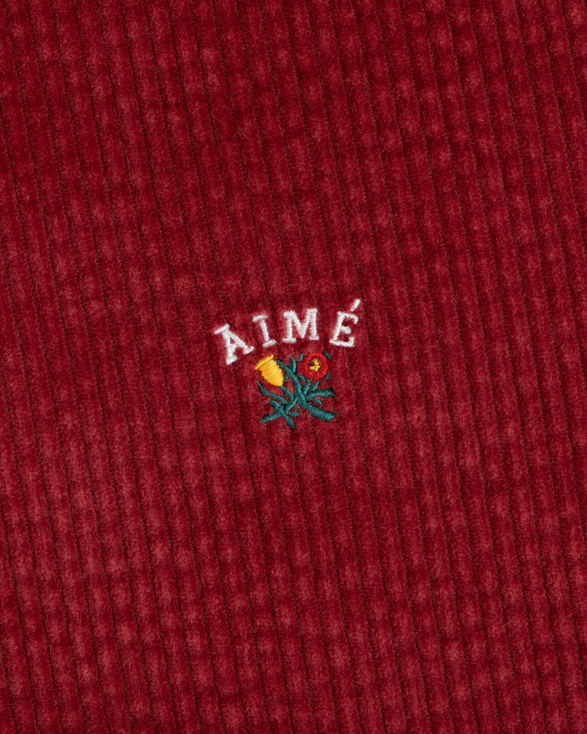 Corduroy Leon Overshirt in deep red corduroy with embroidered AIMÉ text above a small floral design.