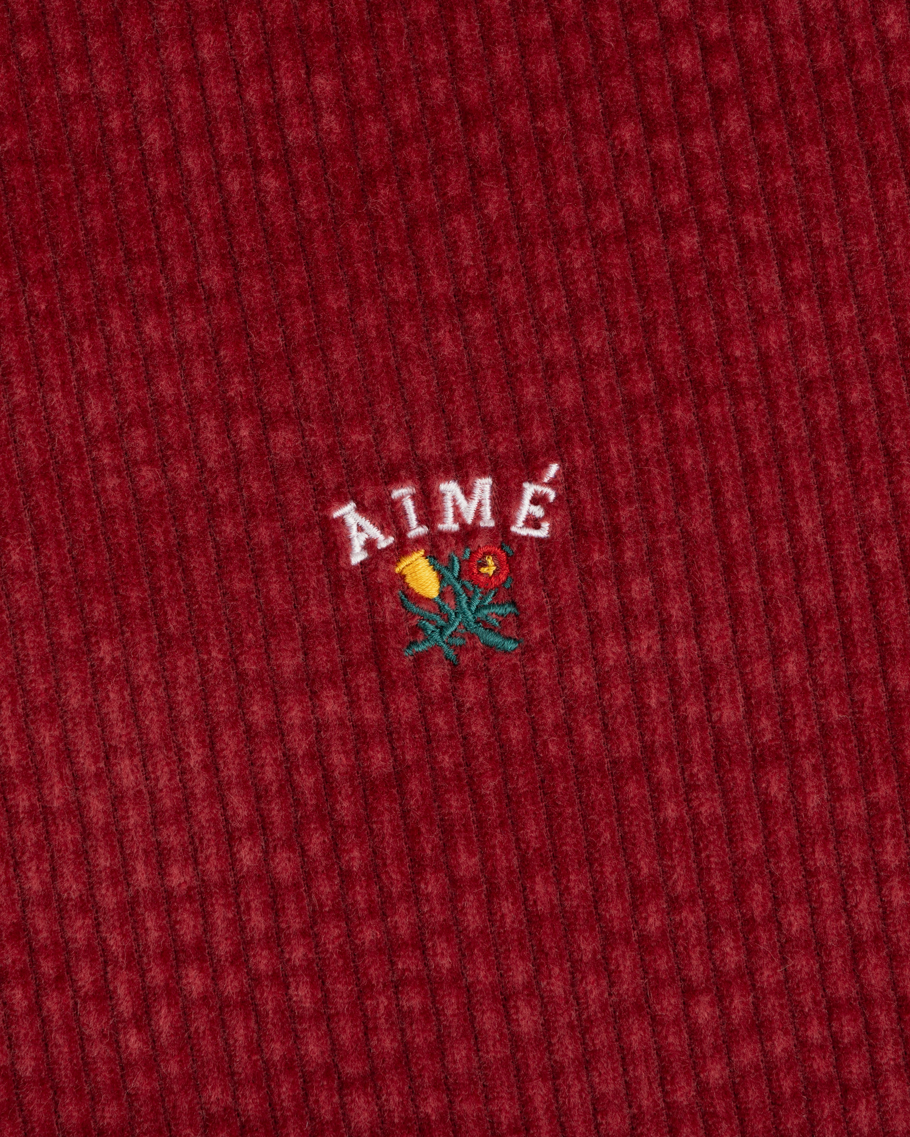 Corduroy Leon Overshirt in deep red corduroy with embroidered AIMÉ text above a small floral design.