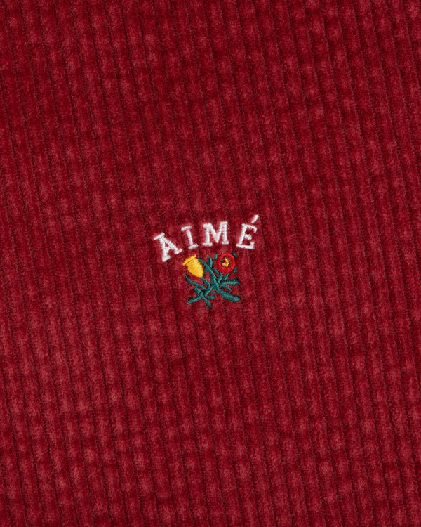 Corduroy Leon Overshirt in deep red corduroy with embroidered AIMÉ text above a small floral design.