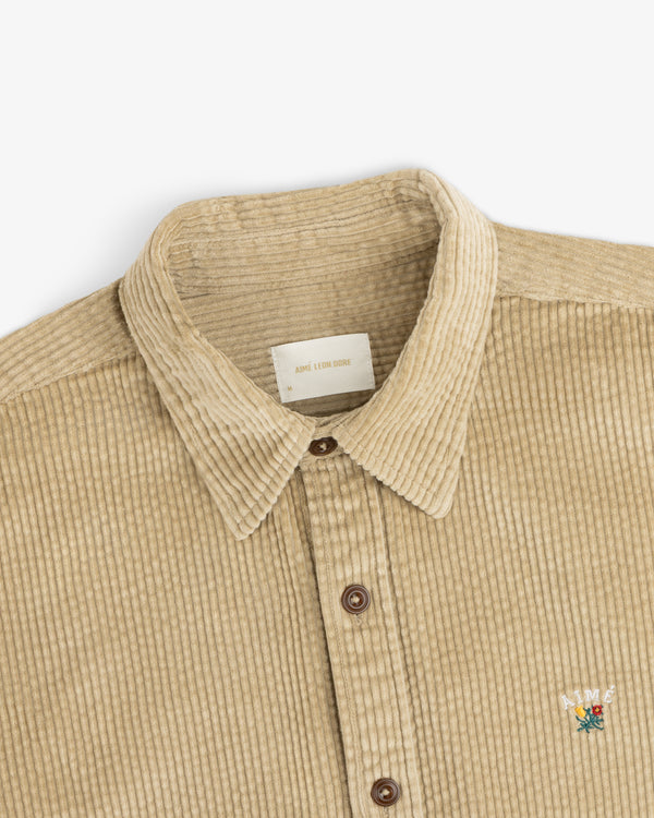 Tan Corduroy Leon Overshirt with a collar, brown buttons, and a small floral embroidery on the chest.