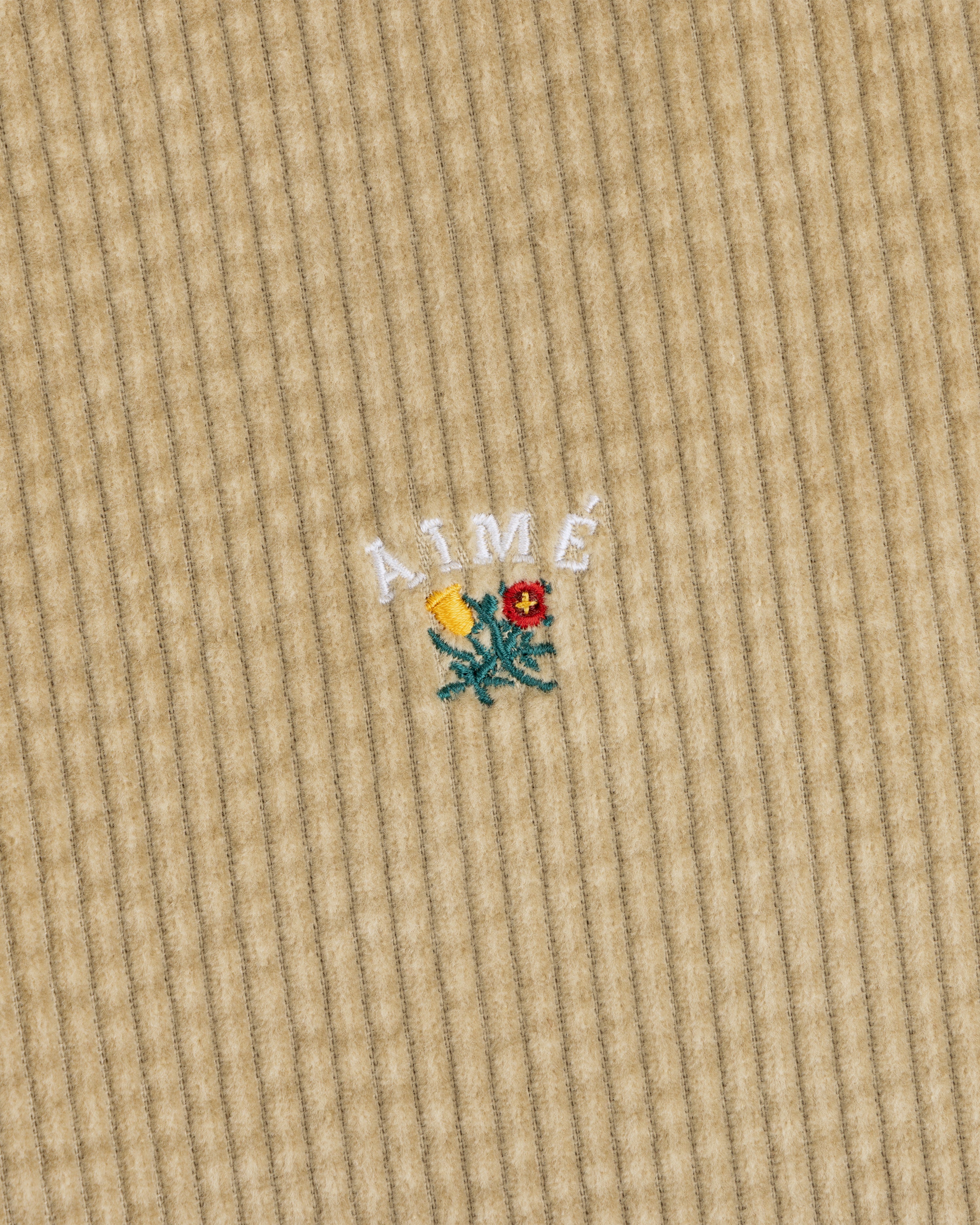 Corduroy Leon Overshirt in tan corduroy with white embroidered Aime text above a small floral design.
