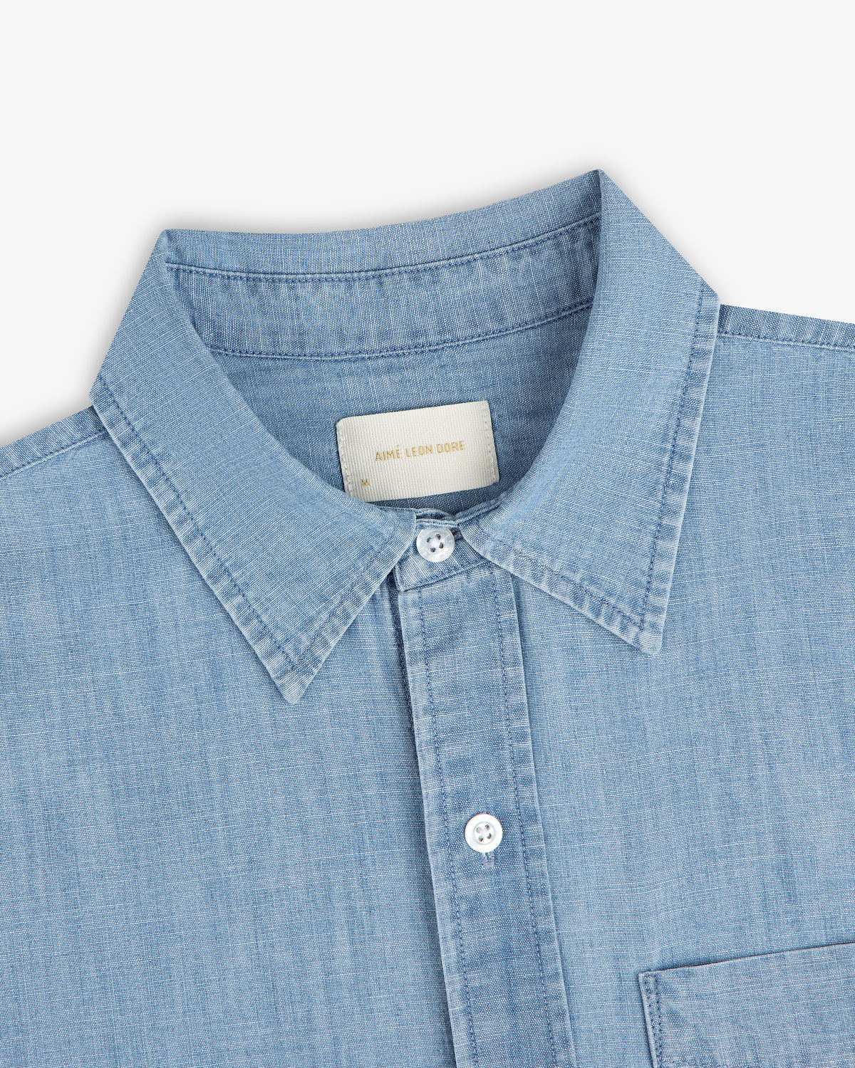 Bayard Chambray Shirt—light blue with a pointed collar, white buttons, and a visible chest pocket.
