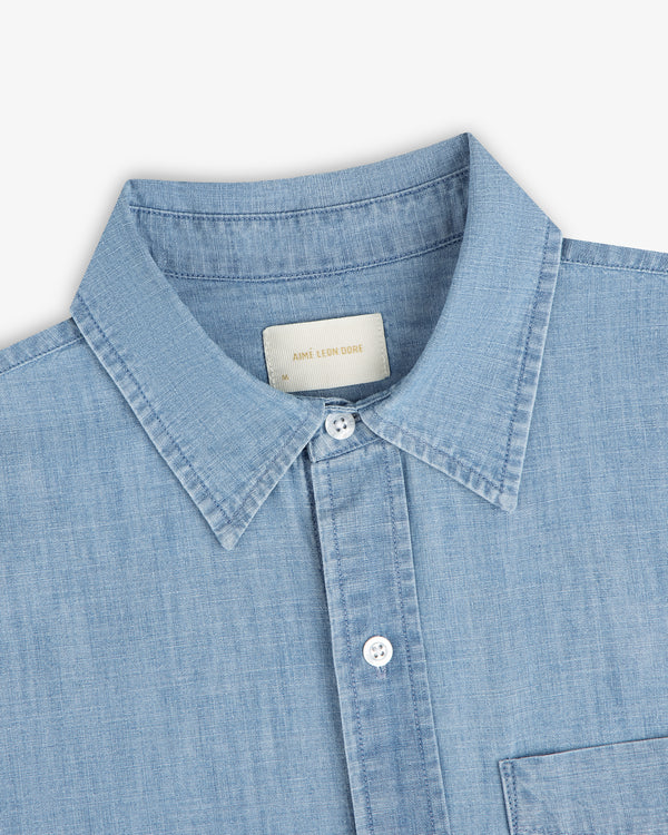 Bayard Chambray Shirt—light blue with a pointed collar, white buttons, and a visible chest pocket.